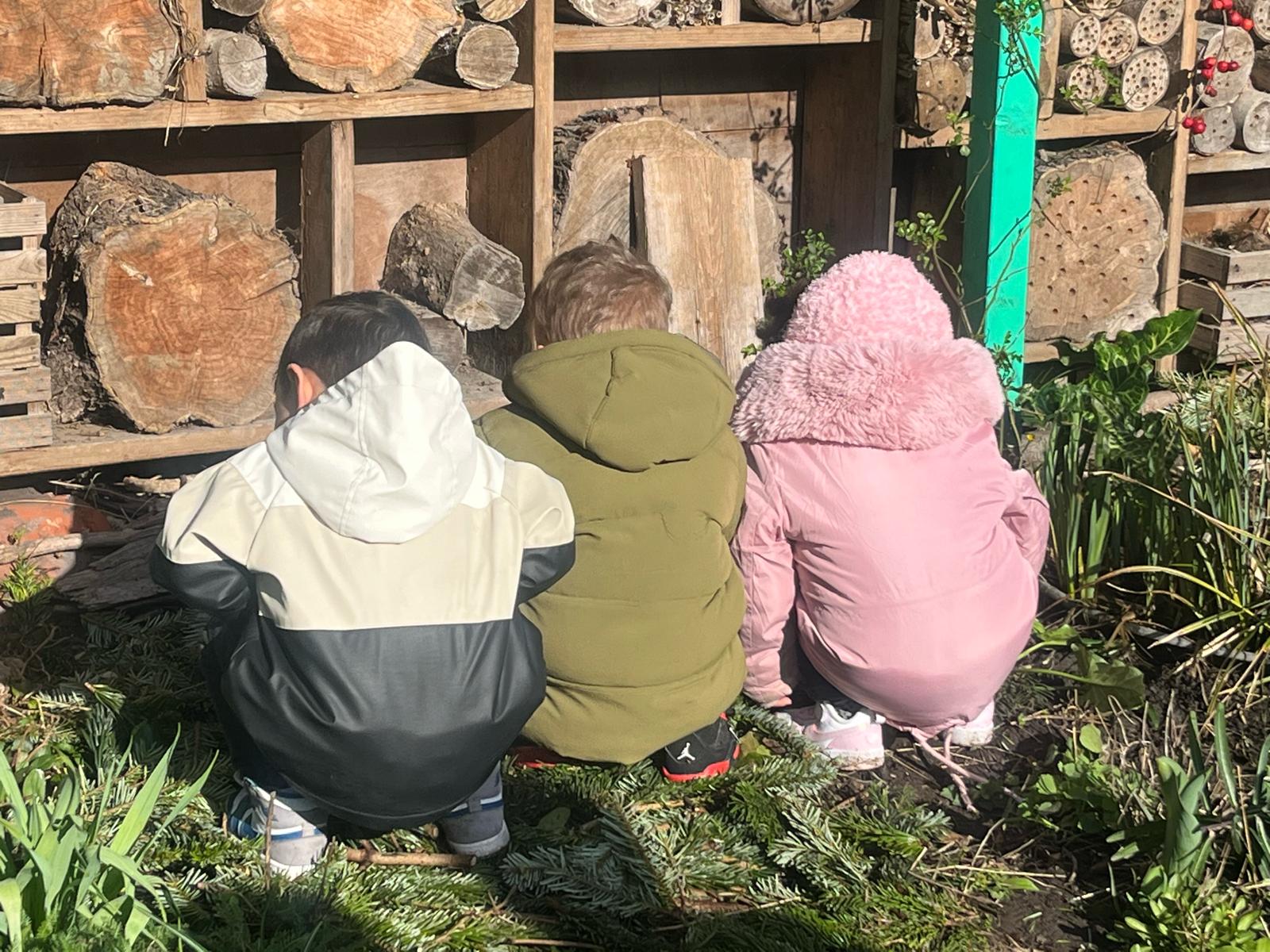Drie kinderen bekijken samen het insectenhotel