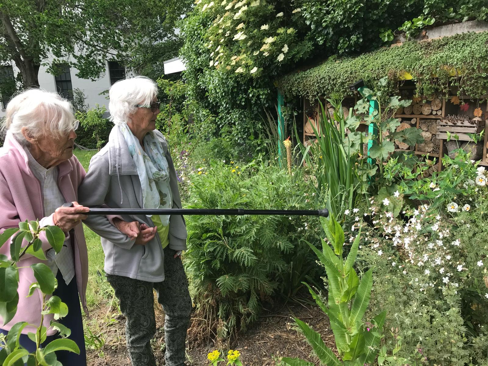 Twee bezoekers bekijken samen het insectenhotel in de tuin