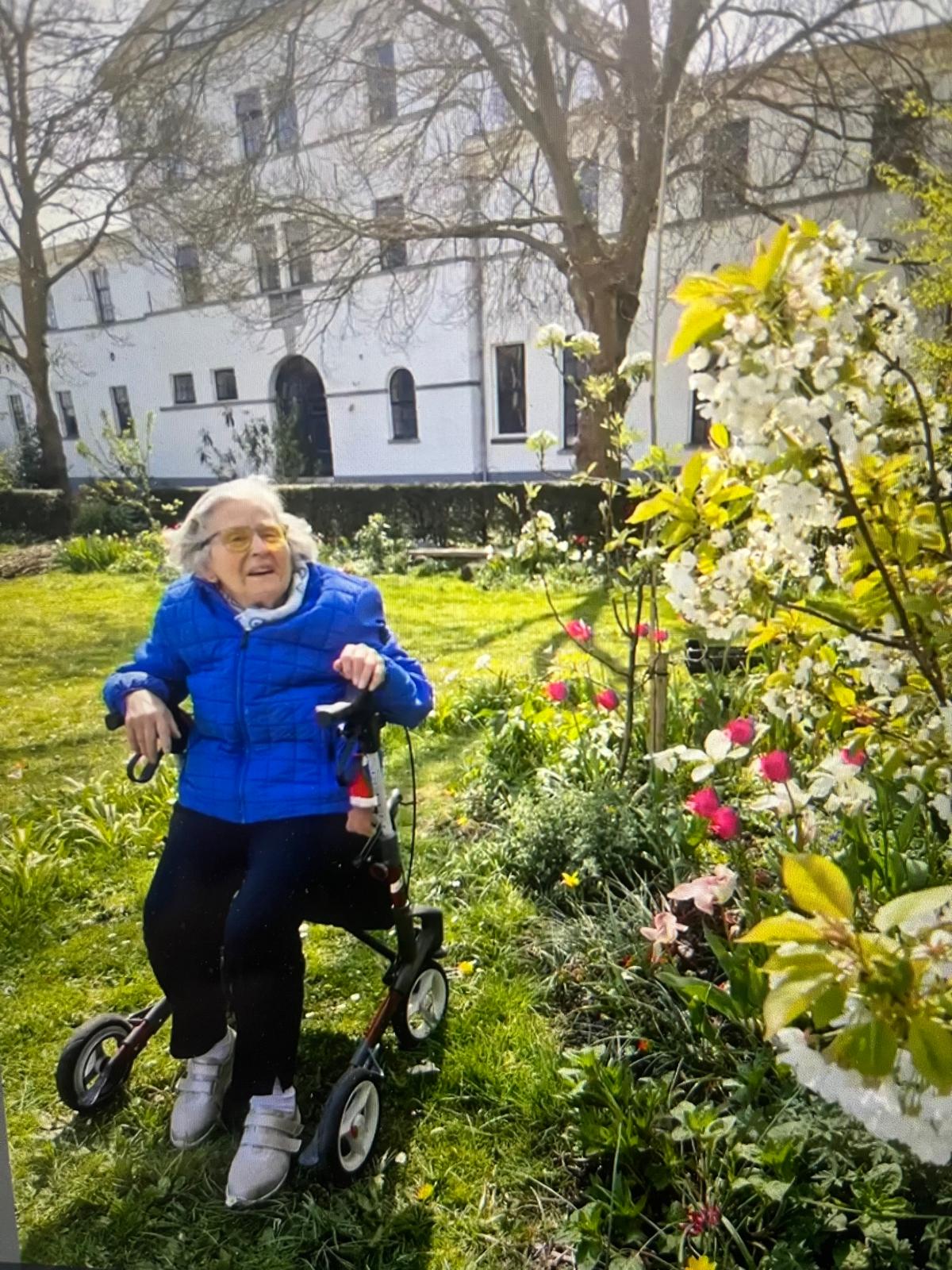 Oudere vrouw met rollator geniet van de voorjaarstuin